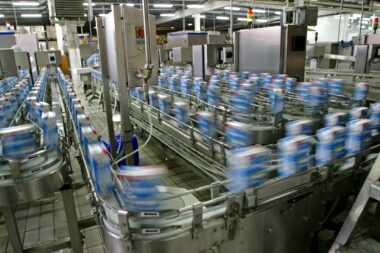 A manufacturing factory showing machines and bottles being transported on conveyor belts.